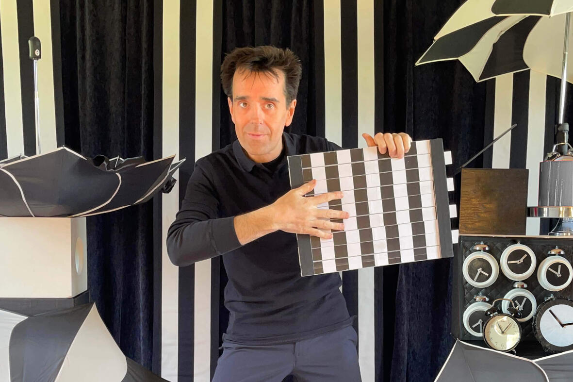 TacticOptik Monsieur Fred sur scène, réalisant un numéro de magie et d’illusion d’optique devant un décor en noir et blanc au moment des festivités de fin d'année.