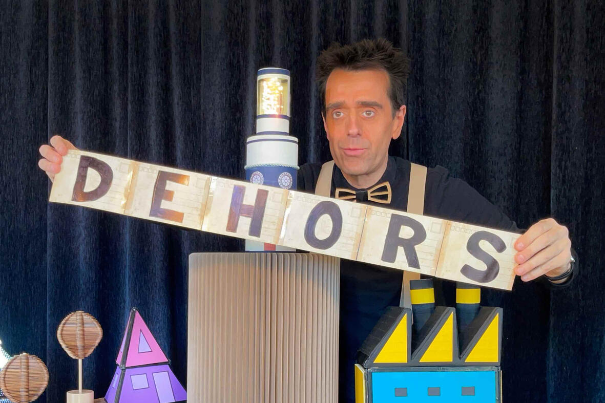 Scène du spectacle “Risque-Tout” : Monsieur Fred, le personnage principal et la petite maison sur l’île, devant un jeune public émerveillé pendant les festivités de la fin d’année scolaire.