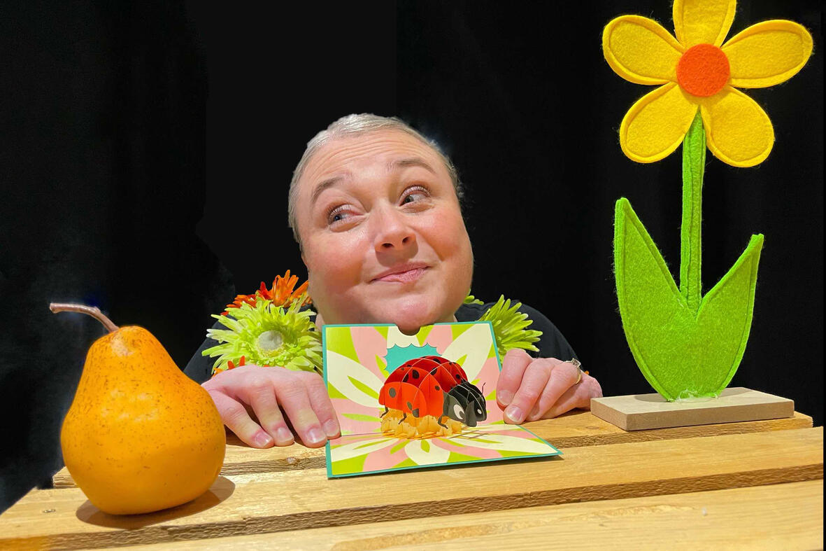 Spectacle j'me cache ! Aurore en pleine représentation, utilisant ses accessoires et personnages dans un décor chaleureux pour captiver le jeune public au temps des fêtes de fin d’année.