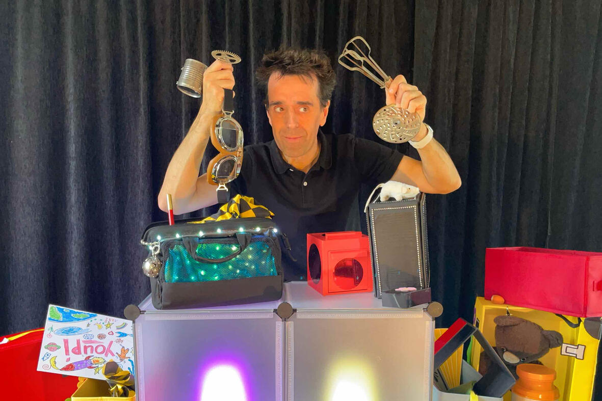 Photo de Monsieur Fred en pleine représentation, entouré de souvenirs et de surprises pour les enfants lors du spectacle “Zouick, fouick, touick” au cœur de la magie de Noël.