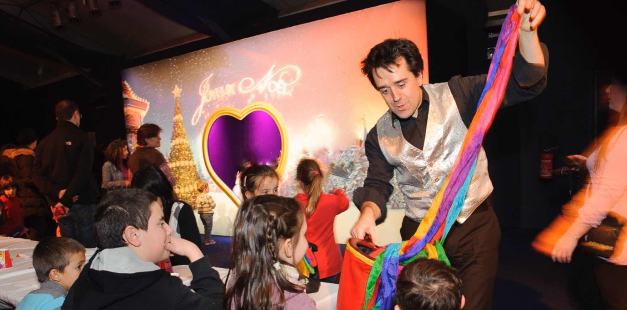 Animation magie de close-up Magicien réalisant un tour de close-up magie devant un petit groupe lors d’une animation événementielle d'arbre de Noël.